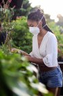 Jeune femme jardinage en masque facial — Photo de stock