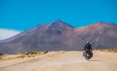 Man riding touring motorcycle on dusty road in Bolivia — Stock Photo