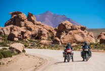 Двое друзей едут на мотоцикле по пыльной дороге в Боливии — стоковое фото