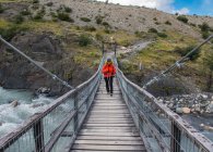 Senderista cruzando puente en el Parque Nacional Torres del Paine - foto de stock