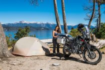 Woman packing motorbike at camp at the Nahuel Huapi Lake in Patagonia — Stock Photo
