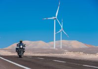 Homem montando sua moto ADV no parque eólico no deserto remoto Atacama — Fotografia de Stock