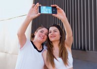 Due amici tengono il telefono in mano per fare un selfie — Foto stock