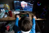 Hohe Ansicht des jugendlichen Jungen, der am Spielcomputer am chaotischen Schreibtisch spielt — Stockfoto