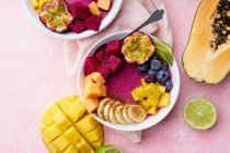 Cuencos de frutas vista superior para un desayuno saludable. Tazones de batido de Pitaya con mango y frutas de verano - foto de stock