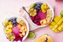 Vista superior de tigelas de frutas para o café da manhã saudável. Duas taças de smoothie pitaya com manga, mamão e frutas de verão — Fotografia de Stock
