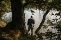 Человек рыбачит в озере среди деревьев — стоковое фото