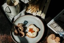 De arriba del pedazo sabroso del pan con la mantequilla y la confitura puestas a la mesa con las nueces y el café fresco - foto de stock