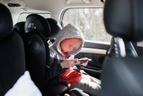 Boy sat in his car seat playing a Nintendo video game console — Stock Photo
