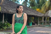 Mujer posa frente a un campamento turístico, mientras mira al horizonte - foto de stock