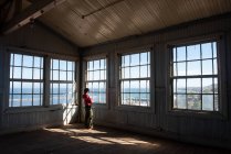 Una mujer mirando a través de unas ventanas en un viejo edificio. - foto de stock