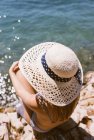 Frau mit Hut sitzt am Strand am Meer — Stockfoto