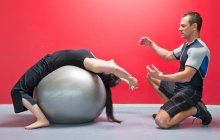 Personal trainer helping client in gym — Stock Photo