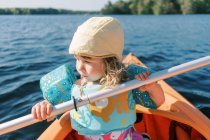 Petite fille essayant de pagayer dans un kayak. — Photo de stock