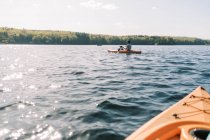 Una famiglia che si gode una giornata estiva di sole in kayak su un lago. — Foto stock