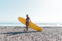 Retrato de uma surfista posando com longboard na praia — Fotografia de Stock