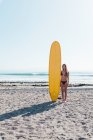 Portrait of a female surfer posing with longboard on the beach — Stock Photo