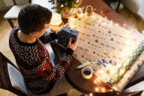 Молодой человек собирает рождественские подарки для друзей и семьи — стоковое фото
