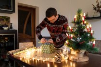 Молодий чоловік пакує різдвяні подарунки для друзів і сім'ї — стокове фото