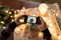 Чоловік фотографує на смартфоні ретельно загорнутий різдвяний подарунок — стокове фото