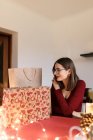 Joven mujer milenaria con regalos de Navidad en un ambiente festivo - foto de stock