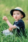 Bonito menino criança sentada na grama alta. — Fotografia de Stock