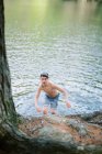 Rapaz a caminhar para a costa depois de um mergulho no lago — Fotografia de Stock