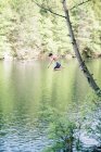 Un niño saltando de un árbol a un lago. - foto de stock