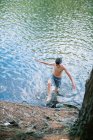 Rapaz a caminhar para a costa depois de um mergulho no lago — Fotografia de Stock