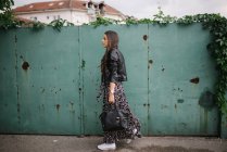 Young woman in dress and leather jacket walking around town — Stock Photo