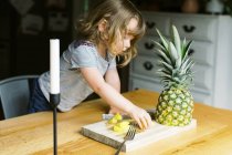 Una bambina che fa uno spuntino sano all'ananas — Foto stock