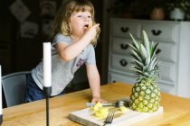 A little toddler girl having a healthy pineapple snack — Stock Photo