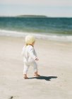 Una niña jugando en la arena en la playa - foto de stock