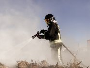 Bombeiros pulverizam água para fogo selvagem. — Fotografia de Stock
