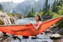 Mulher está relaxando em uma rede no lago alpino em férias locais — Fotografia de Stock