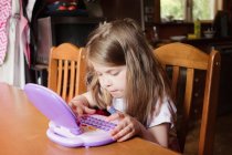 Chica joven jugando en la tableta preescolar - foto de stock
