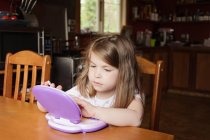 Young girl sitting and playing on preschool tablet — Stock Photo