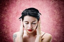 Femme souffrant de migraine, devant un mur rose — Photo de stock