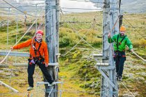 Dos hombres balanceándose en pista de obstáculos de cuerda alta en Islandia - foto de stock
