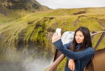 Hermosa mujer tomando selfie en la cascada de Skogarfoss en Islandia - foto de stock