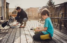 Father and son working on fixing a deck with power tools together. — Stock Photo