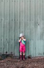 A young girl stands near a barn wearing a leotard and cowgirl boots. — Stock Photo