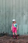 Une jeune fille se tient près d'une grange portant un justaucorps et des bottes de cow-girl. — Photo de stock