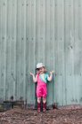 A young girl stands near a barn wearing a leotard and cowgirl boots. — Stock Photo
