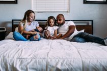 Une famille se blottissant sur le lit avec le nouveau-né — Photo de stock