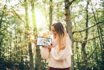 Pretty girl poses in nature with tablet — Stock Photo