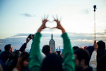 Menschen beobachten von Wolkenkratzern aus die Gebäude von New York bei Sonnenuntergang und machen Fotos mit den mobilen, vereinigten Staaten — Stockfoto