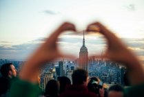 Люди дивляться з хмарочосів будівлі Нью - Йорка на заході сонця і фотографують їх за допомогою мобільного телефону, Сполучені Штати Америки. — стокове фото