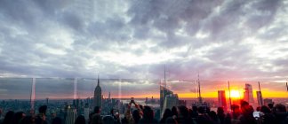 People watch from skyscrapers the buildings of New York at sunset and — Stock Photo