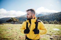 Joven con chaqueta amarilla y mochila en las montañas. - foto de stock